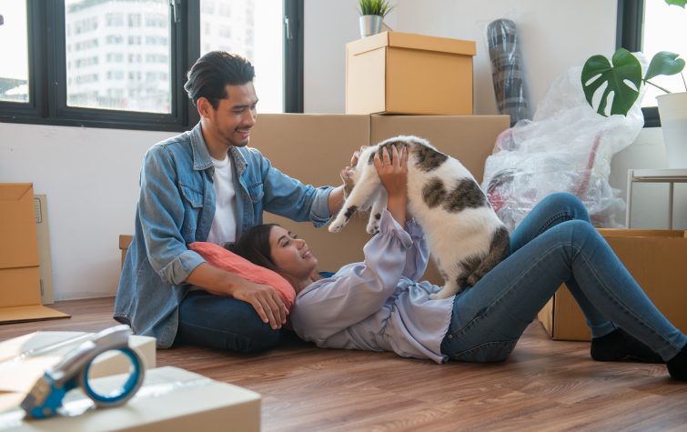 Young Asian couple moving into new home with cat