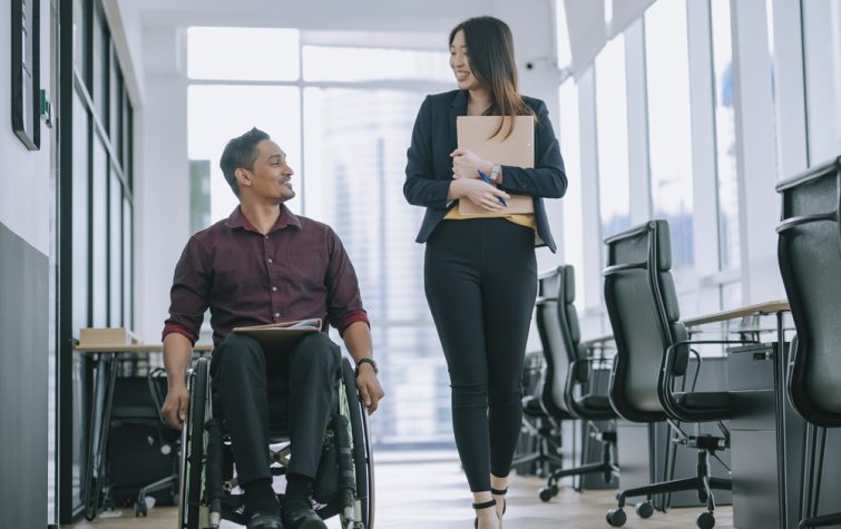Man in wheelchair and woman coworkers roam office together